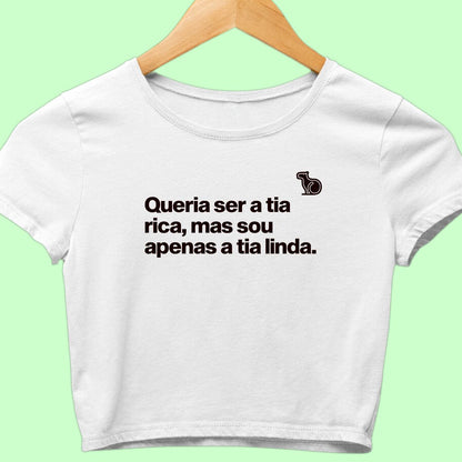 Camiseta cropped com a frase "Queria ser a tia rica, mas sou apenas a tia linda." branca.